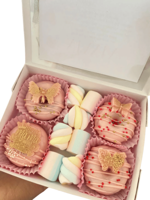 caja de 4 donas cubiertas de chocolate rosada decoradas con toper de chocolate y masmellos